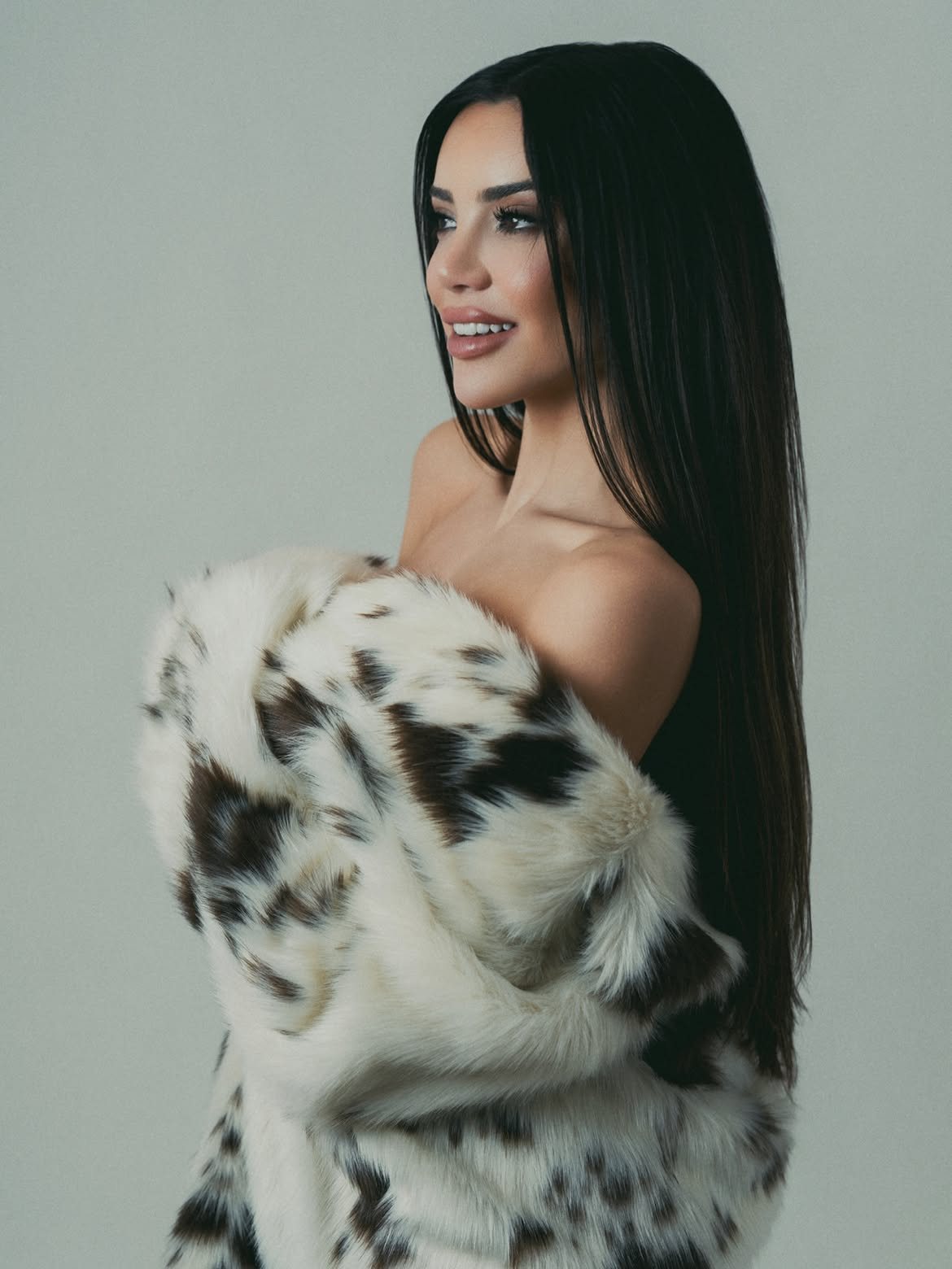 Eileen León in profile, smiling, a spotted fur coat slipping off her shoulders