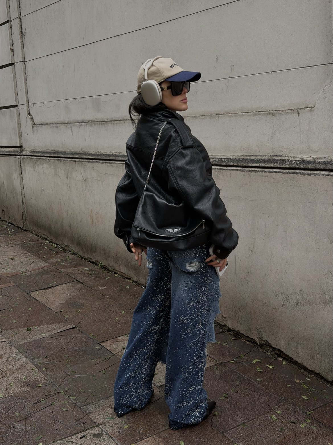 Looking back over the shoulder in an oversized leather jacket and crystal-studded jeans