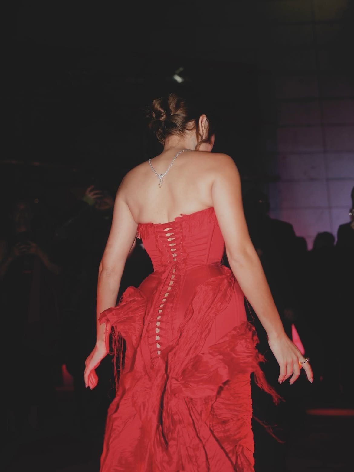 The laced back of the red corset gown in the dark