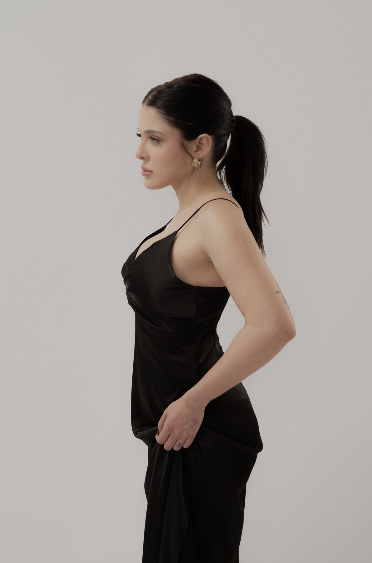 Sofía Gonet in strict profile, sleek ponytail, black slip dress