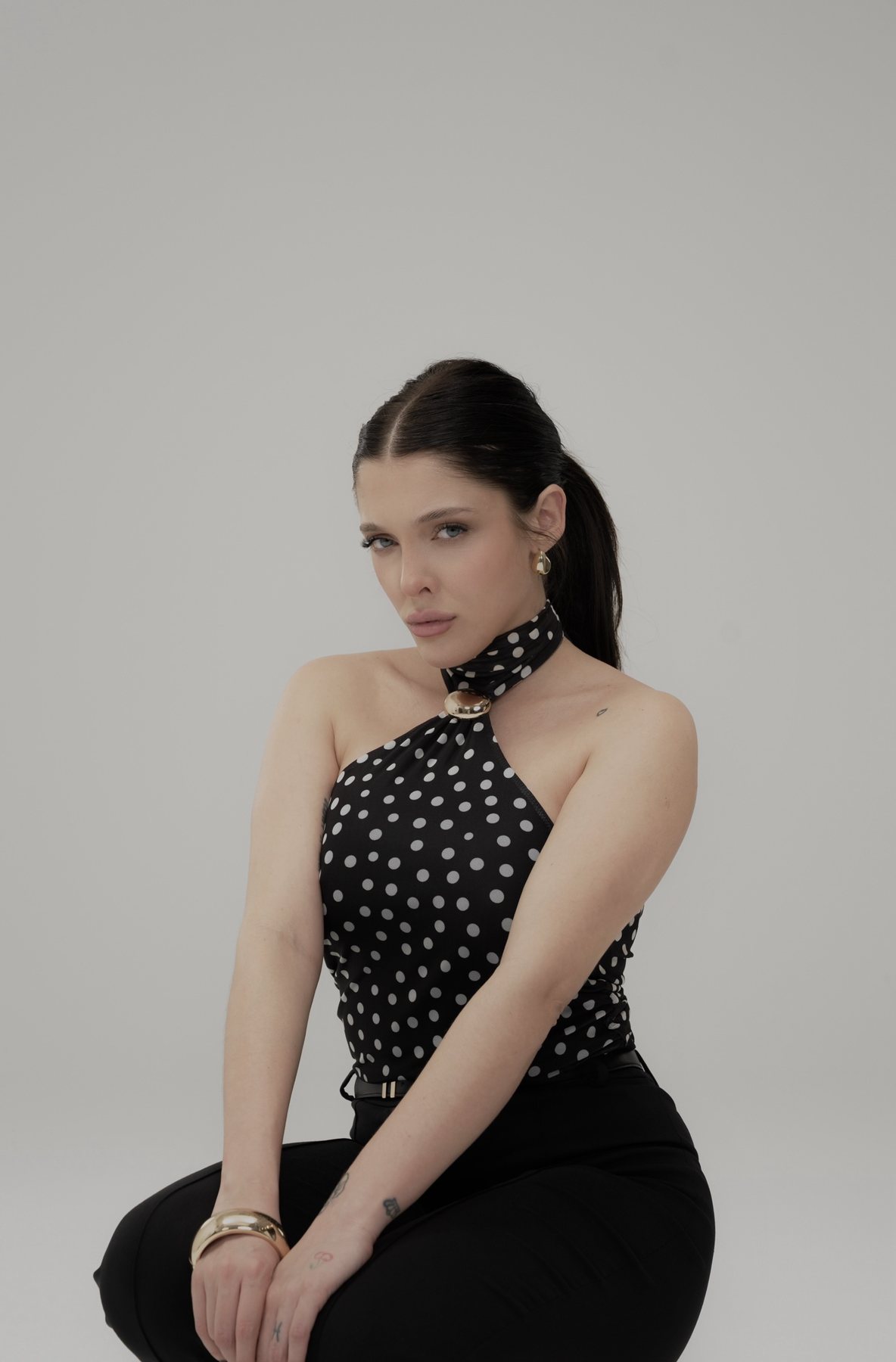 Sofía Gonet seated in a polka-dot halter top with a gold clasp