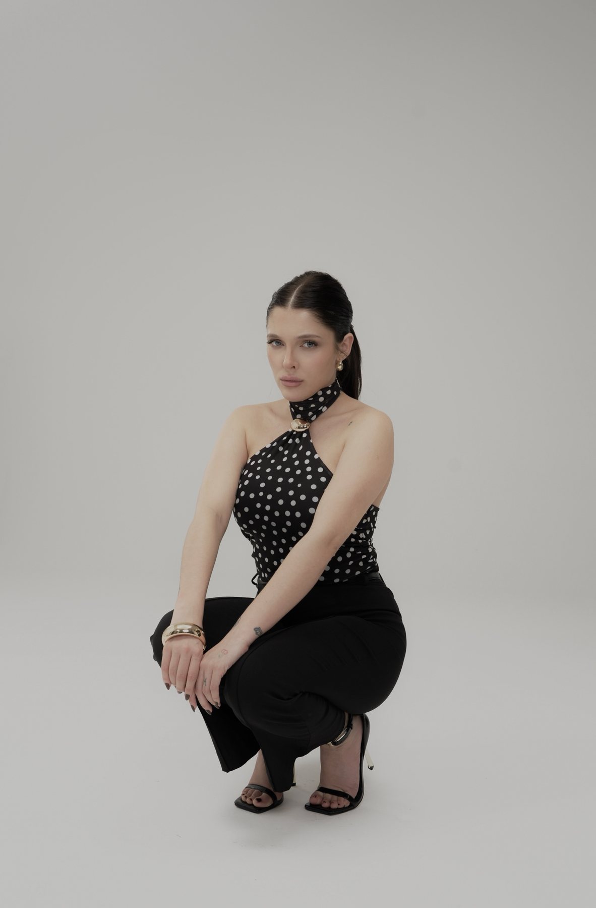 Sofía Gonet crouching in the polka-dot halter and black trousers