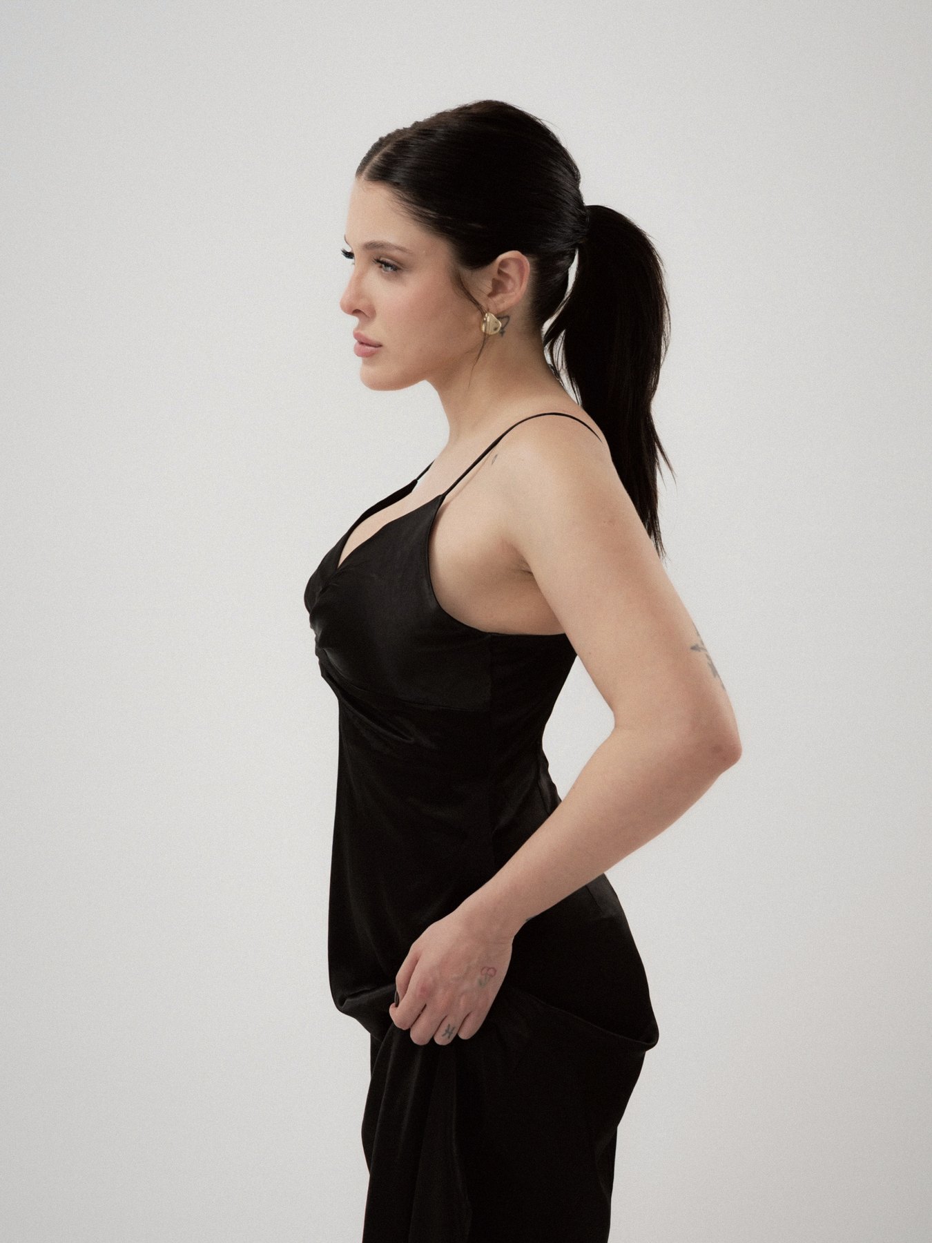 Sofía Gonet in strict profile, sleek ponytail, black slip dress