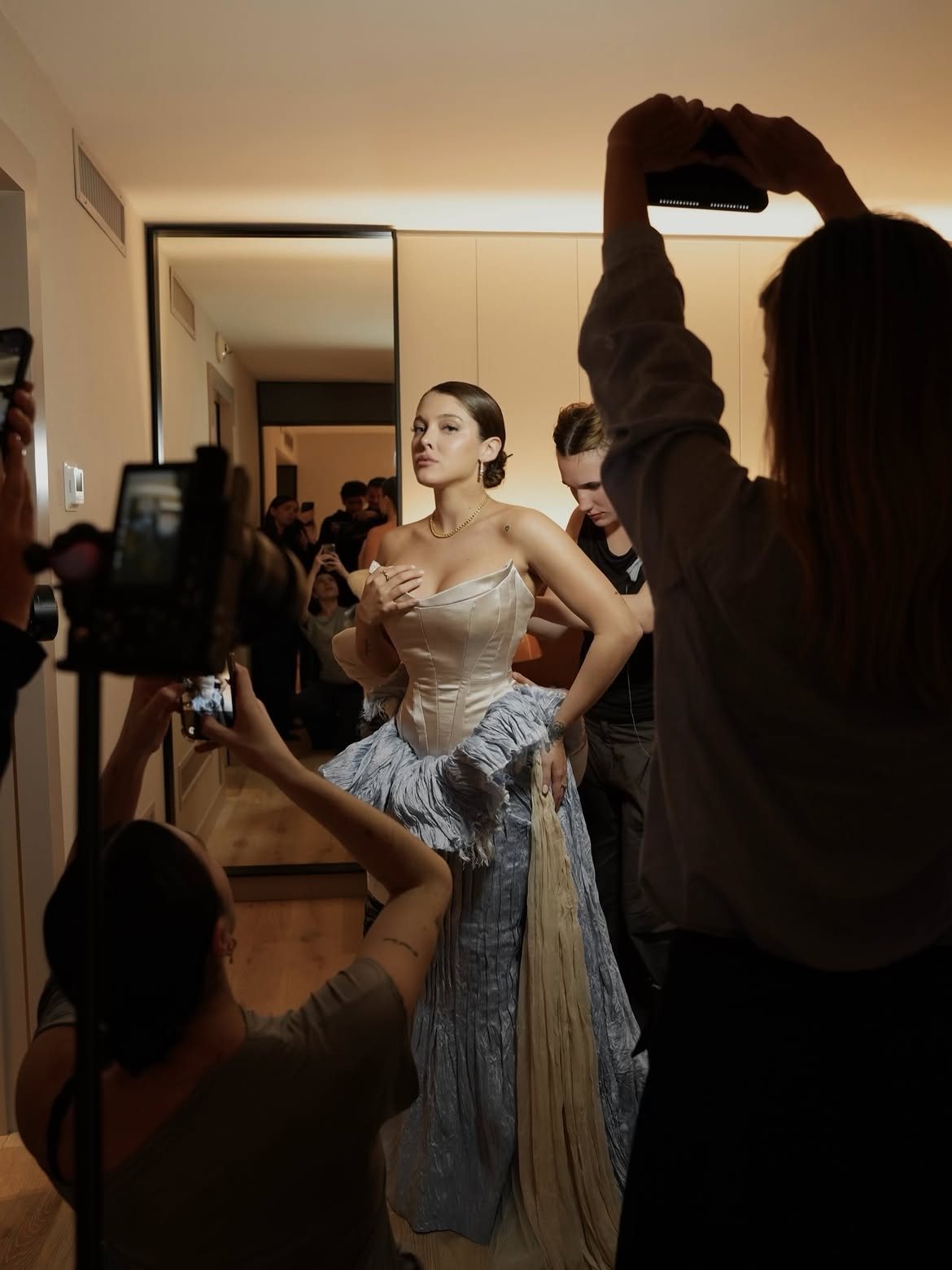 Sofía Gonet being dressed in a hotel room, surrounded by phones and cameras