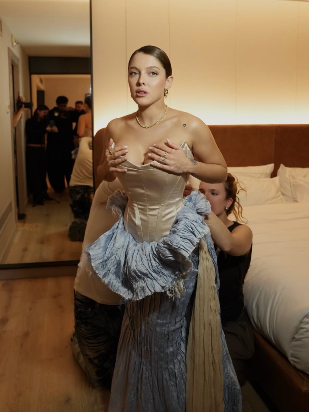 Sofía Gonet holding her satin corset as the team fits the pale blue skirt