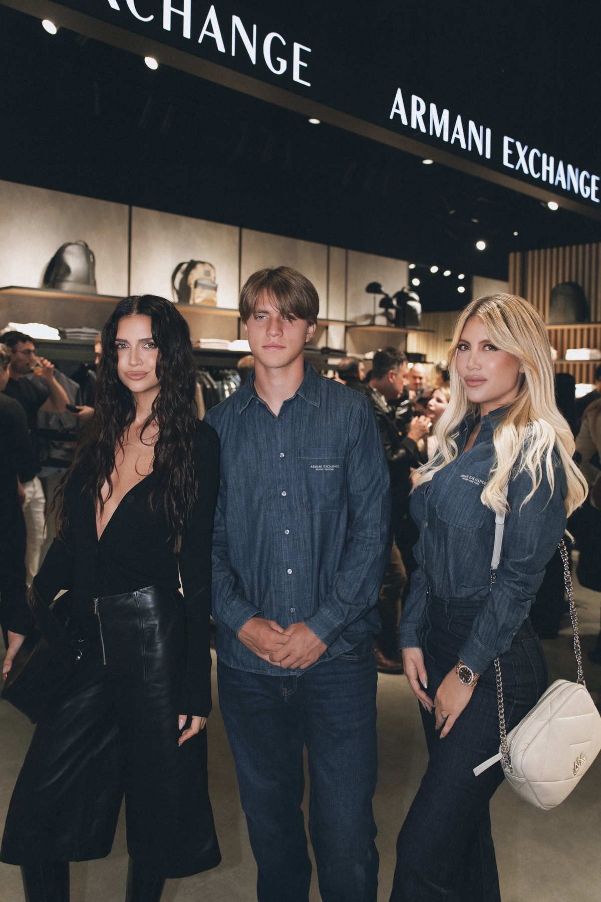 Three guests at the Armani Exchange opening under the illuminated store sign
